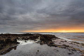 Fantástico pôr do Sol na praia rochosa