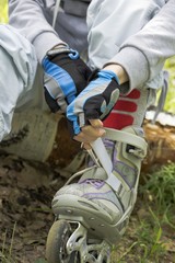 	Two hands girls removing roller skates.Summer in the Park.

Two hands girls removing roller...
