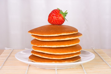 Stack of pancakes with a fresh strawberry on top