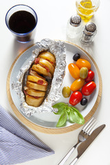 baked potato in foil. ripe red and yellow cherry tomatoes and ol
