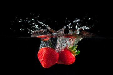 Strawberries splashing into water