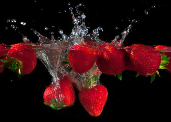 Strawberries splashing into water