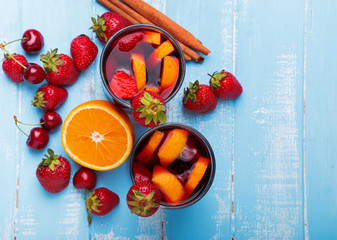 Glasses with sangria, cherries, strawberries on the blue wooden