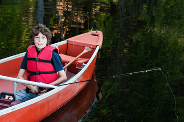 Fototapeta premium boy wearing a life-jacket fishing in a canoe