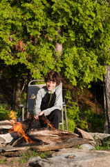 boy sitting by a campfire roasting marshmallows