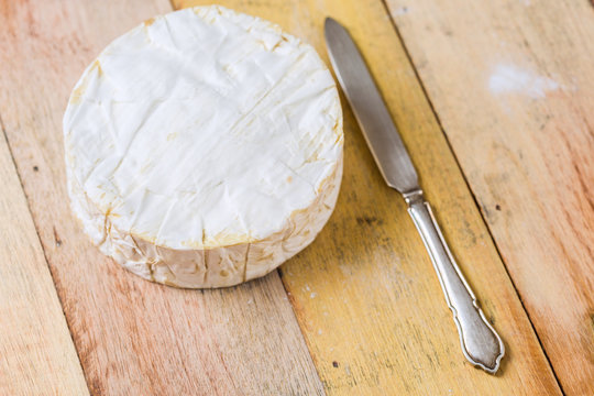 Camembert cheese and vintage knife on wooden table