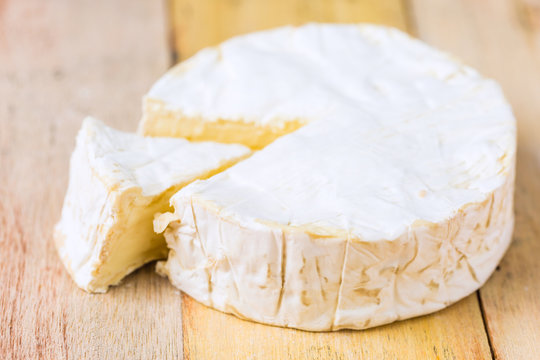 Camembert cheese wrapped in paper with vintage knife on wooden table