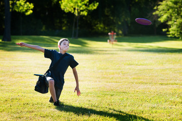 young boy playing disc golf in a park