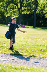 young boy playing disc golf in a park