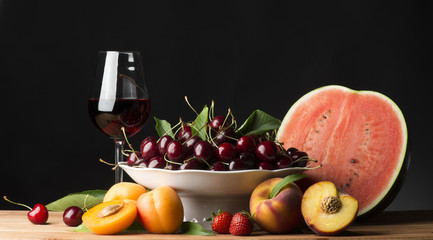 summer fruits on the wooden table with glass of wine