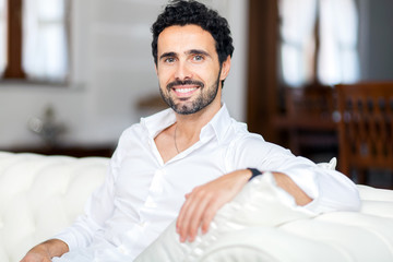 Happy smiling man relaxing and sitting on sofa at home