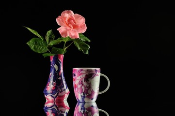 pink rose in colorfull porcelain vase and colorfull coffecup