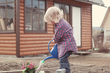 Little girl planting and watering flowers in garden © rimmdream