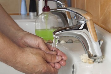 Man washing his hands in the sink. Hygiene in the home bathroom.
