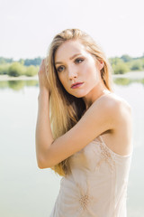 Fototapeta na wymiar Sexy blonde girl posing on the lake shore, emotive expresson