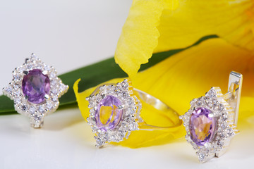 Beautiful gold ring and earrings with gemstones on a yellow flower.