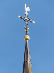 Kirchturmspitze mit vergoldetem Wetterhahn der Bartholomäuskirche vor blauem Himmel im...