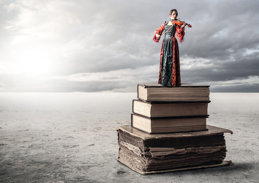 Woman playing he violin while standing on a pile of books
