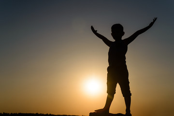 Fototapeta premium Silhouette of Young Boy Standing with Open Arms