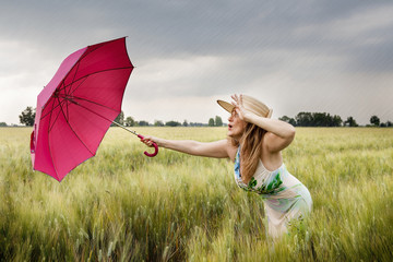 pretty woman with umbrella in a field of wheat ears