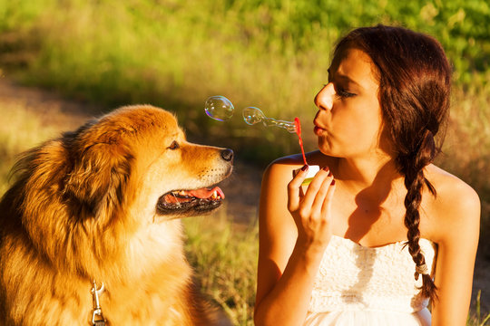 h&uuml;bsches junges M&auml;dchen macht Seifenblasen vor einem Elo-Hund