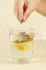 Hand puts the tea bag in a cup of water