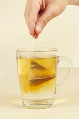 Hand brews tea bag in a cup of boiling water