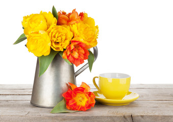 Colorful tulips bouquet in watering can and coffee cup