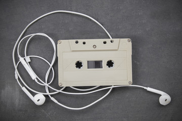 White earphones on analog audio cassette background music concept