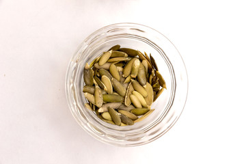 Pumpkin seeds in a glass cup on a white wooden table