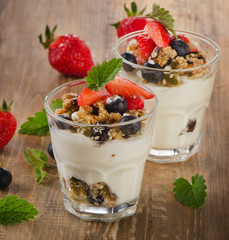 Yogurt with Granola  and fresh berries on a rustic wooden backgr