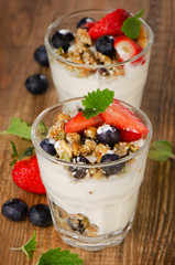 Yogurt with Granola  and fresh berries on wooden background.