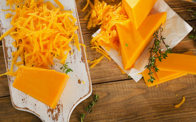 Cheddar Cheese on white wooden cutting Board. - obrazy, fototapety, plakaty