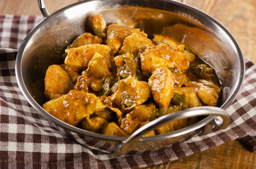 Chicken curry in  balti dish on a wooden table.