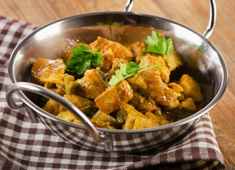 Chicken curry in  balti dish on  wooden table.