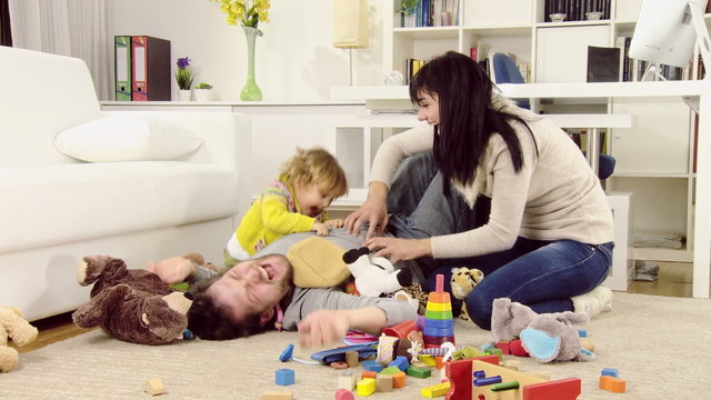 Wife and daughter tickeling father in living room