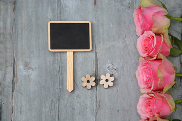 row of pink yellow roses on a old used wooden background with black chalk board and empty spaceand empty space