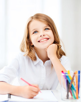 smiling little student girl drawing at school