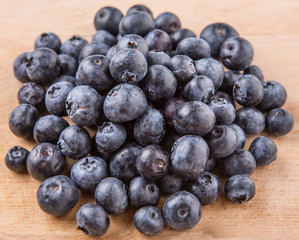 Blueberry fruits in a white bowl on wooden board background