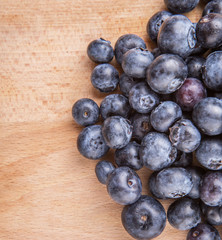 Blueberry fruits in a white bowl on wooden board background