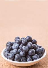 Blueberry in a white bowl on cork board background