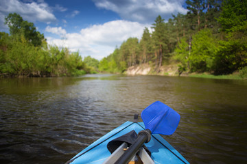Blue paddles are lying on kayak. Kayaking on a river