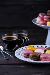 Fresh vibrant macaroons on plate with coffee