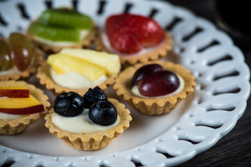 Fresh fruits tarltlets pastry with cream on plate