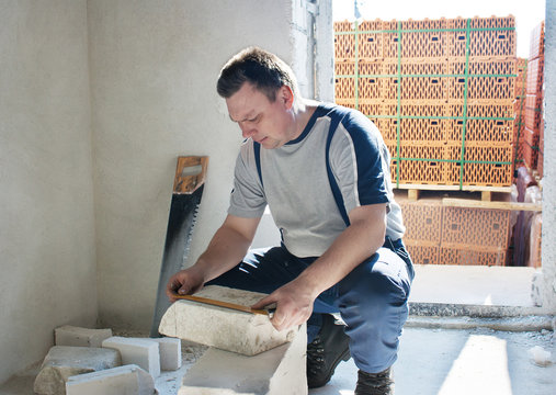 Man measuring a silicate brick with a ruler
