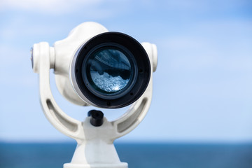 White paid telescope stands on sea coast