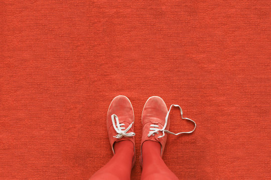 Overhead view of a woman's legs and shoes with a heart made out her shoelaces, all in red