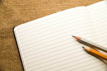 Opened notebook and pencils on the old tissue