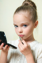 Fashion little girl applying make up. Mascara, eye shadow, lip g