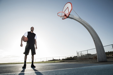 Portrait of young basketball player holding a ball in court